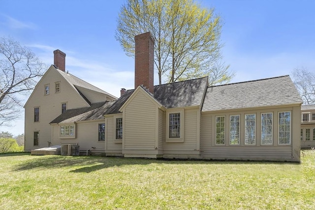 rear view of house with a chimney, a yard, and cooling unit
