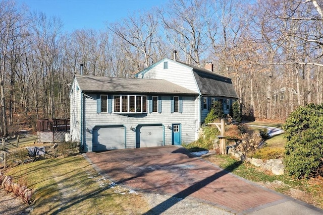 view of front of property with roof with shingles, a chimney, a gambrel roof, a garage, and driveway