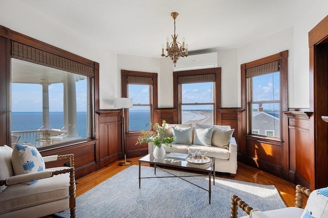 2 Bluff Rd, Hull, MA 02045 - living area featuring wainscoting, a chandelier, a wall mounted AC, wood finished floors, and a water view