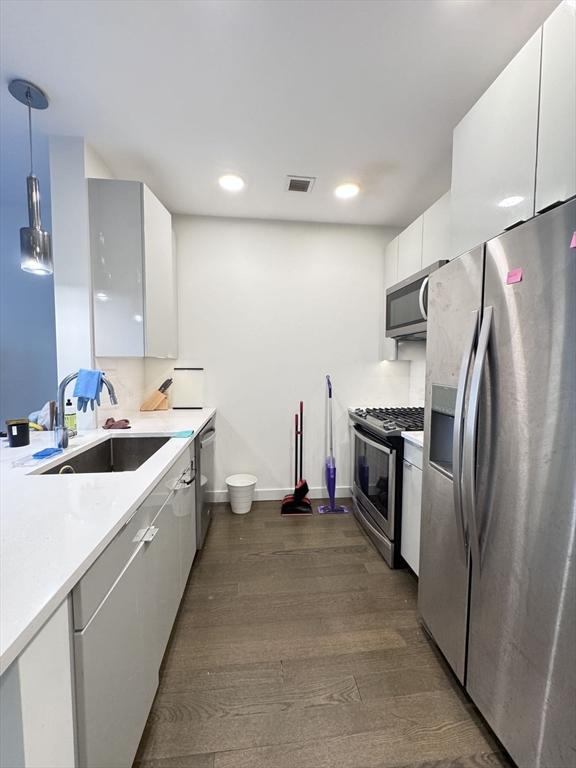 kitchen featuring appliances with stainless steel finishes, white cabinetry, dark wood-type flooring, and sink