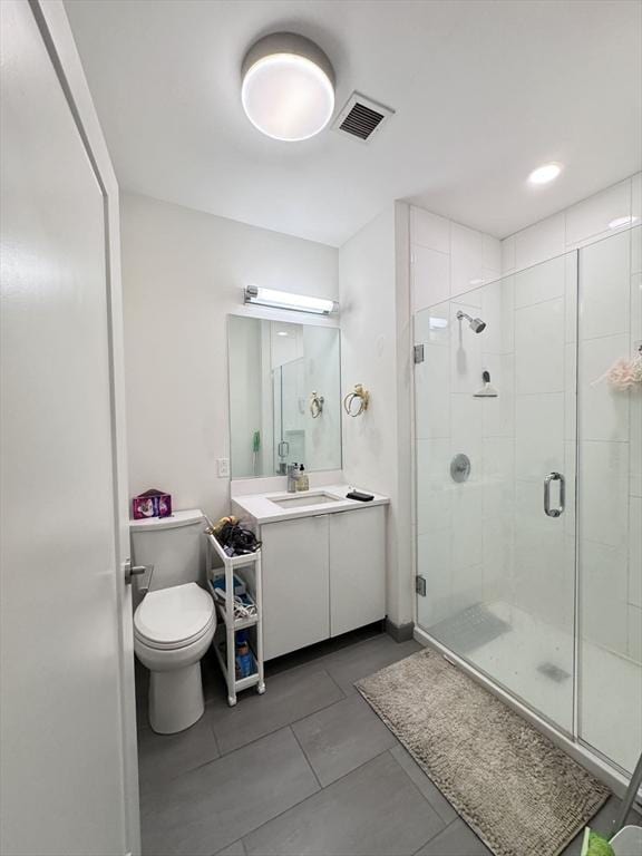 bathroom featuring tile patterned floors, vanity, toilet, and a shower with door