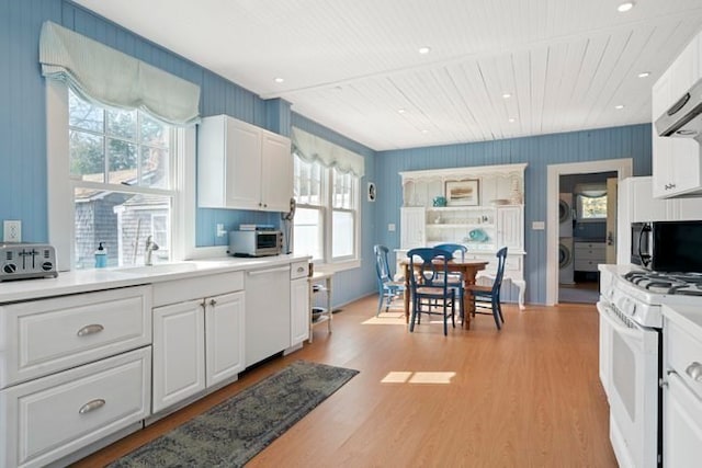 kitchen with sink, white appliances, white cabinetry, and light hardwood / wood-style flooring