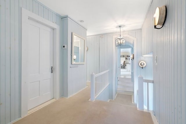 hallway with a notable chandelier and light carpet