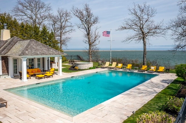 view of pool featuring a jacuzzi, a water view, an outdoor structure, and a patio area