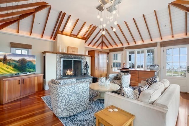 living room with beamed ceiling, a fireplace, an inviting chandelier, and hardwood / wood-style flooring