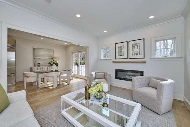 living area featuring a glass covered fireplace, french doors, a healthy amount of sunlight, and ornamental molding