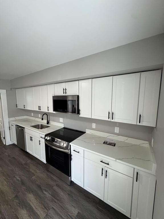 32 Main St, Monson, MA 01057 - kitchen with appliances with stainless steel finishes, dark wood-style flooring, white cabinets, and light stone counters