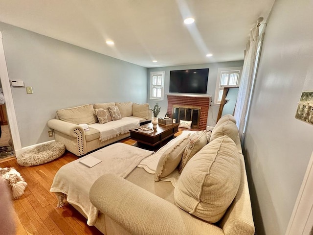 living area featuring baseboards, a brick fireplace, wood finished floors, and recessed lighting