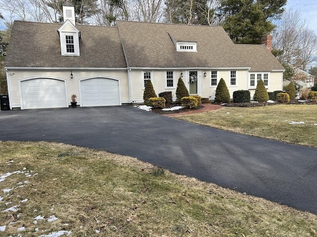 cape cod-style house featuring a garage, a shingled roof, a front lawn, and aphalt driveway