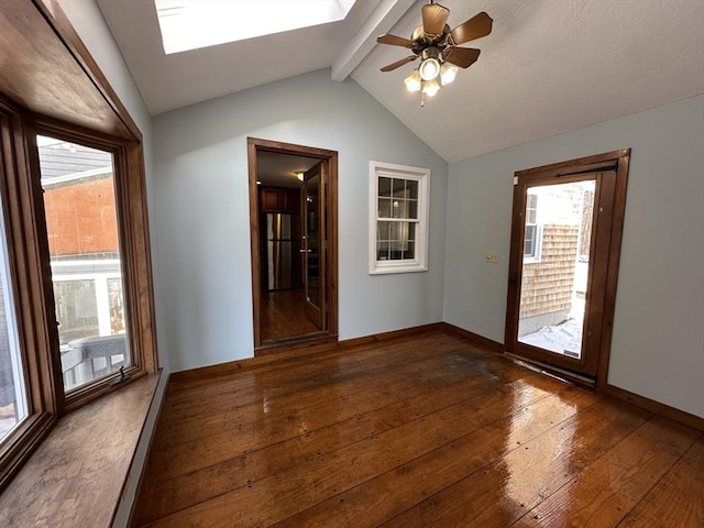 unfurnished room featuring lofted ceiling with skylight, dark hardwood / wood-style floors, and ceiling fan