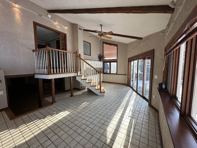 entryway with tile patterned flooring, ceiling fan, lofted ceiling with beams, and a textured ceiling