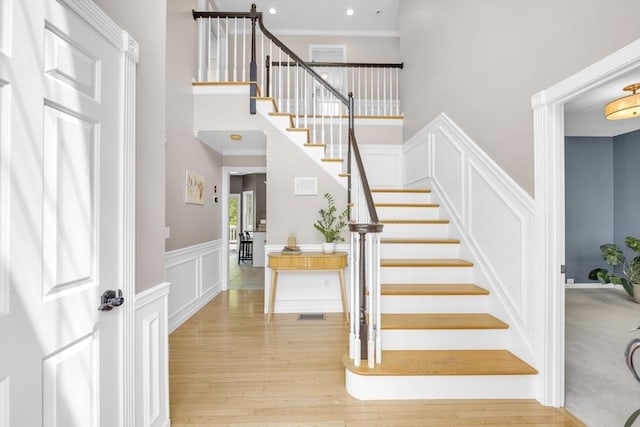 18 Preserve Way, Sturbridge, MA 01566 - stairway featuring a high ceiling, a decorative wall, wood finished floors, a wainscoted wall, and crown molding