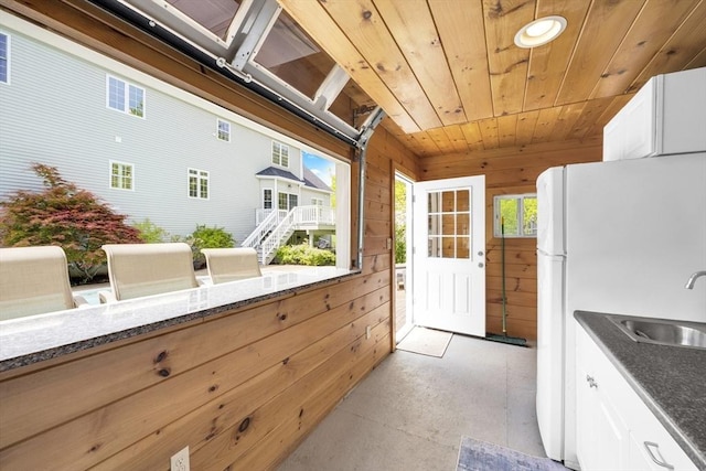 18 Preserve Way, Sturbridge, MA 01566 - kitchen featuring a sink, wood ceiling, white cabinetry, wooden walls, and finished concrete floors