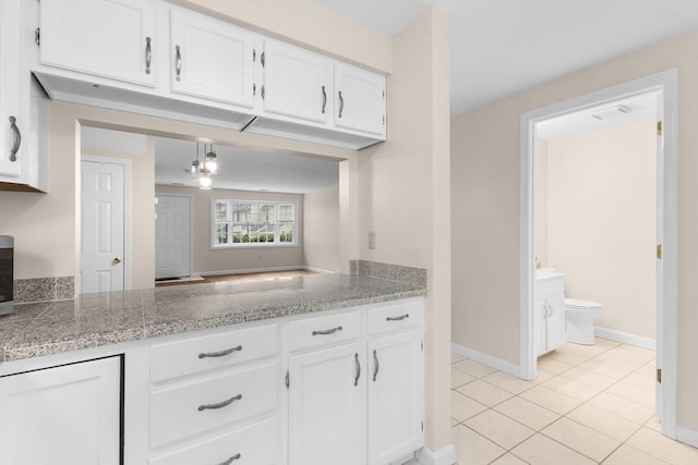 kitchen with white cabinetry, light tile patterned floors, baseboards, and tile counters