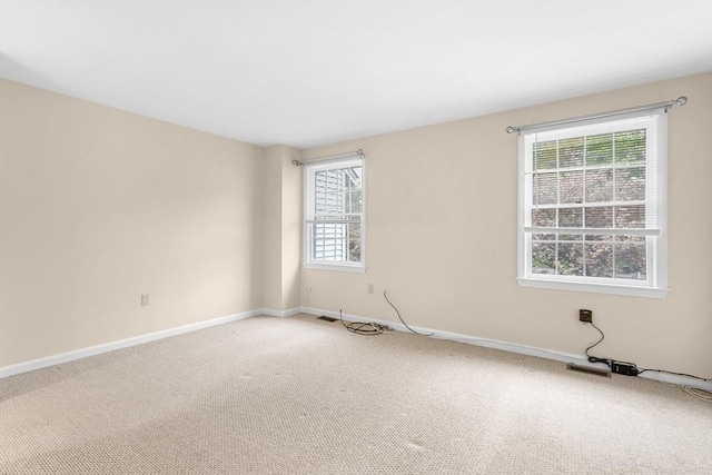 unfurnished room with light colored carpet and baseboards