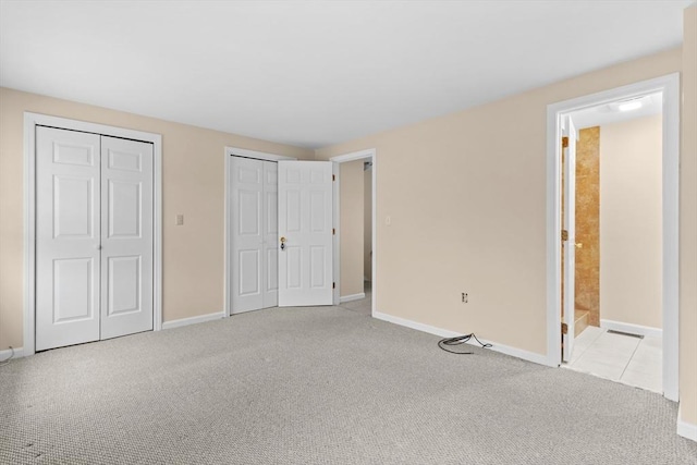 unfurnished bedroom with two closets, carpet flooring, and baseboards