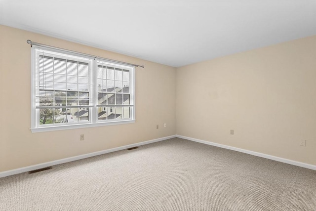 spare room featuring carpet floors and baseboards