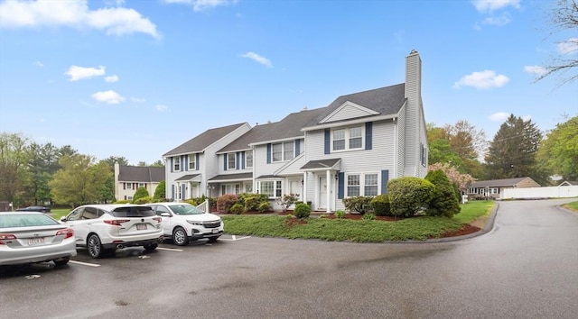 multi unit property featuring a chimney, uncovered parking, and a residential view