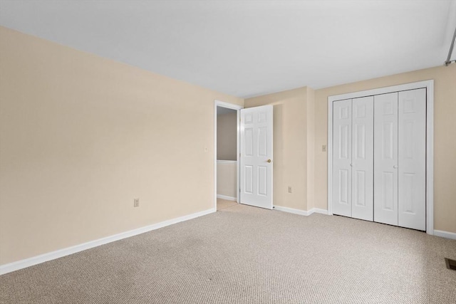 unfurnished bedroom with baseboards, light colored carpet, and a closet