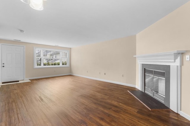 unfurnished living room with wood finished floors, baseboards, and a glass covered fireplace