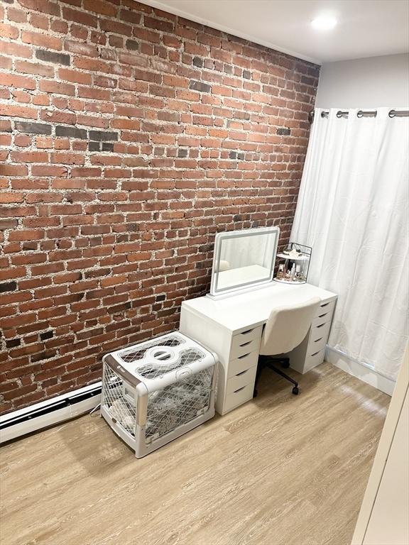 office with brick wall and light hardwood / wood-style flooring