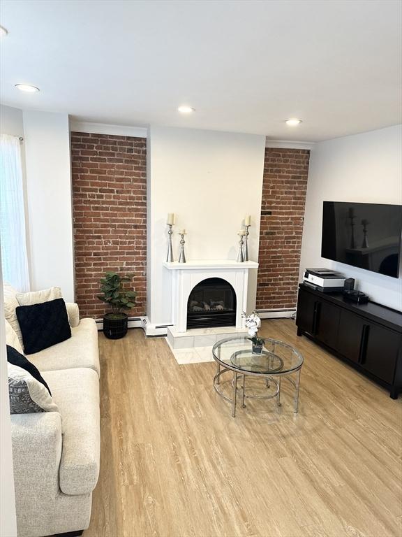 living room with wood-type flooring and a large fireplace