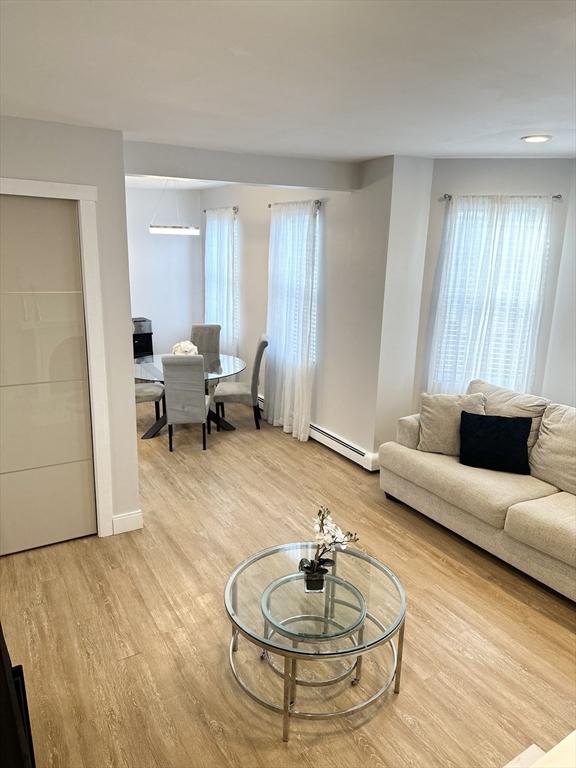 living room featuring baseboard heating and light hardwood / wood-style floors