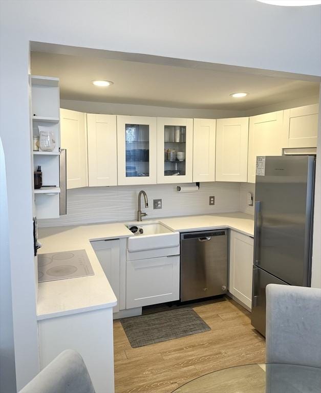 kitchen featuring sink, stainless steel appliances, light hardwood / wood-style flooring, and white cabinetry