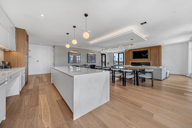191 Washington St Unit 318, Boston, MA 02135 - kitchen with modern cabinets, a spacious island, white cabinetry, hanging light fixtures, and light wood finished floors