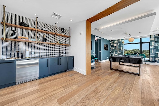 191 Washington St Unit 318, Boston, MA 02135 - kitchen featuring light wood finished floors, baseboards, a wall of windows, a sink, and blue cabinets