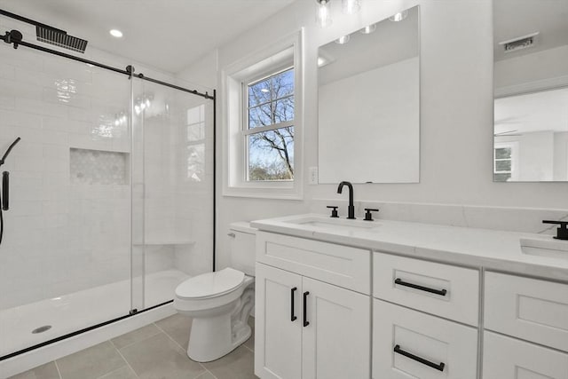 bathroom featuring toilet, vanity, a shower with door, and tile patterned floors