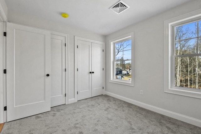 unfurnished bedroom featuring light carpet and multiple closets