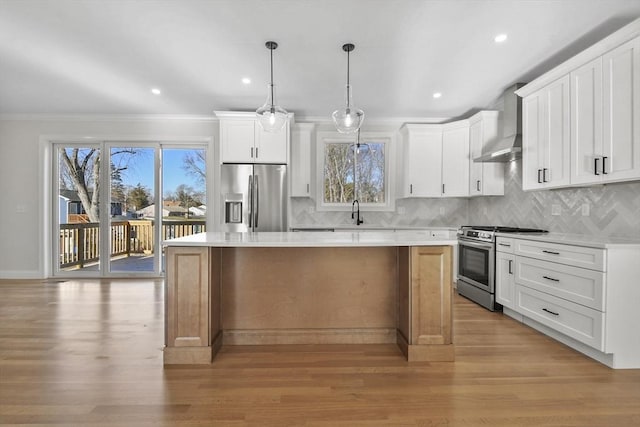 kitchen featuring wall chimney range hood, white cabinets, a center island, and stainless steel appliances