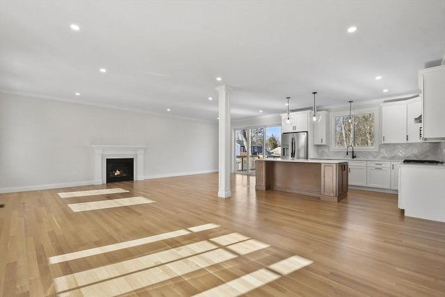 kitchen featuring pendant lighting, a kitchen island, white cabinetry, light hardwood / wood-style floors, and stainless steel fridge