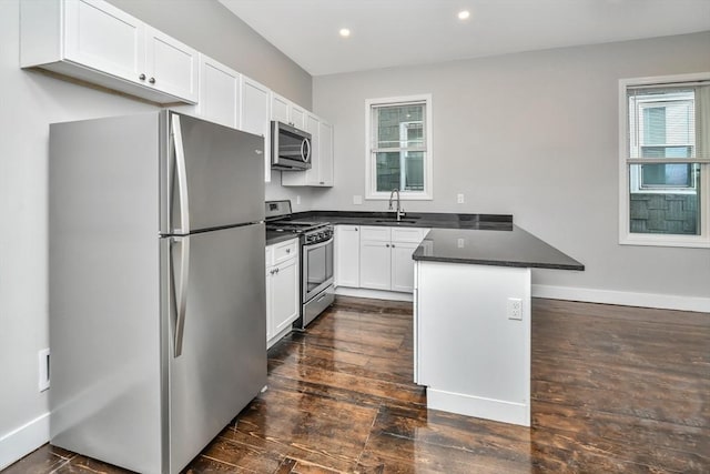 kitchen with white cabinetry, a kitchen bar, kitchen peninsula, appliances with stainless steel finishes, and sink