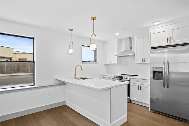 kitchen featuring sink, white cabinetry, wall chimney range hood, appliances with stainless steel finishes, and light stone countertops