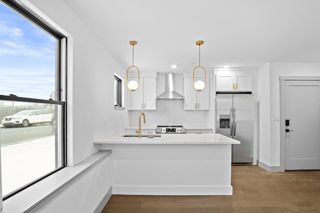 kitchen with appliances with stainless steel finishes, sink, wall chimney range hood, and white cabinets