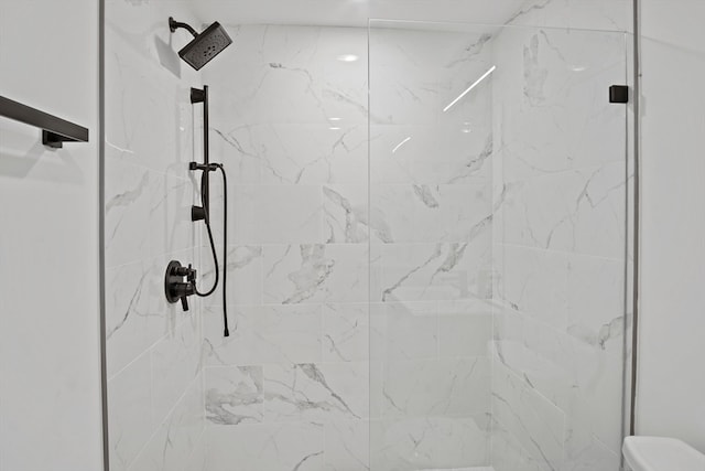 interior details with a shower with shower door and toilet