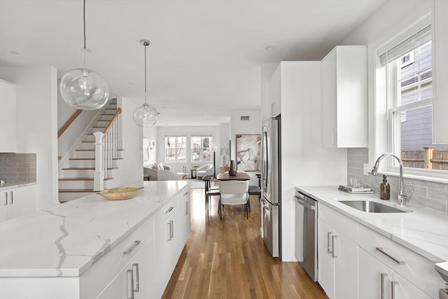 kitchen featuring sink, pendant lighting, decorative backsplash, white cabinets, and appliances with stainless steel finishes