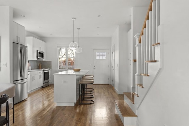 kitchen featuring white cabinets, pendant lighting, a kitchen island, and stainless steel appliances