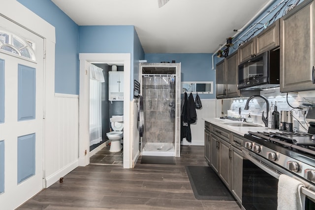 kitchen featuring high end stainless steel range, dark hardwood / wood-style flooring, dark brown cabinets, and sink