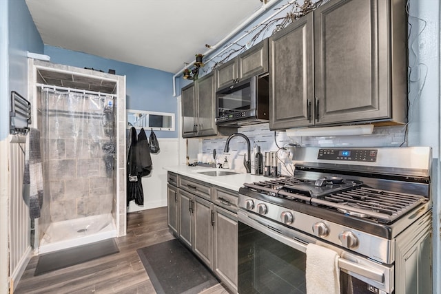 kitchen featuring dark hardwood / wood-style floors, sink, decorative backsplash, and stainless steel gas range oven