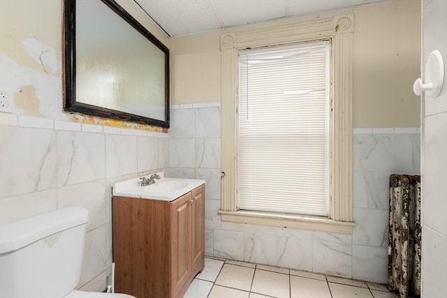 bathroom with tile patterned floors, tile walls, toilet, and vanity