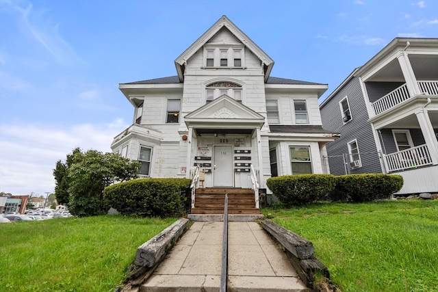 view of front of home with a balcony and a front lawn