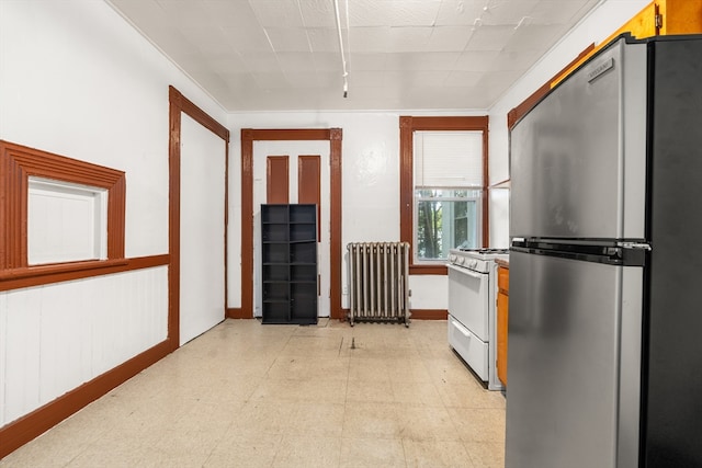 kitchen featuring white gas range, radiator, and stainless steel fridge