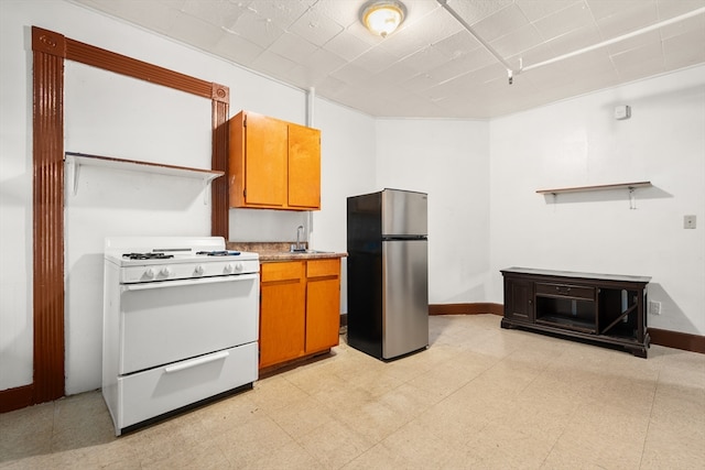 kitchen featuring white gas stove, sink, and stainless steel fridge