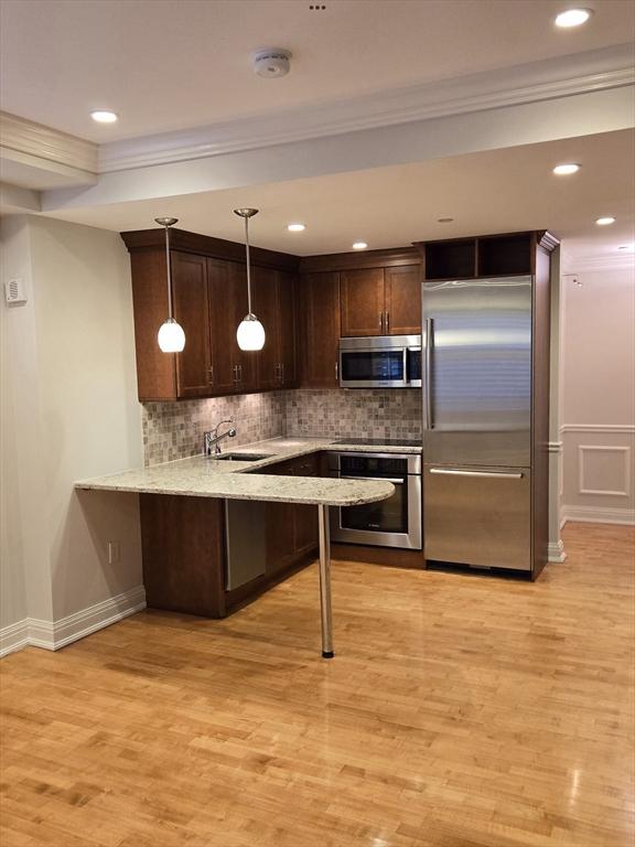 kitchen with stainless steel appliances, light wood-style floors, a sink, and dark brown cabinets