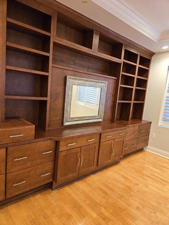 interior space with built in shelves, light wood-style floors, baseboards, and crown molding