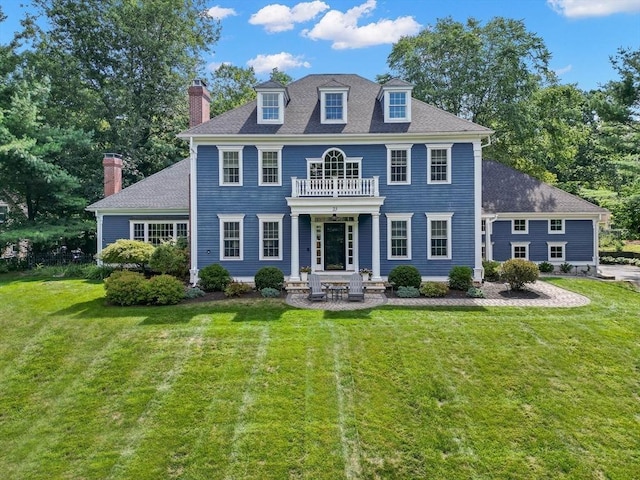 colonial inspired home with a front yard and a balcony