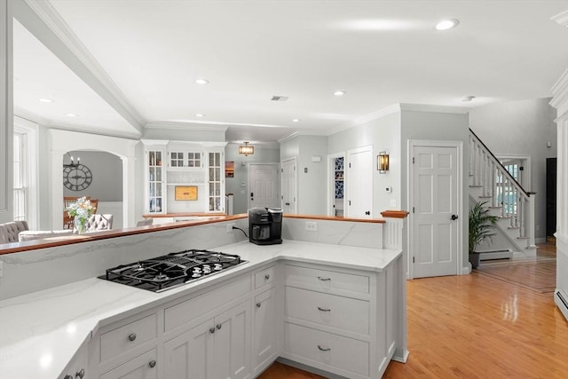 kitchen featuring light stone countertops, stainless steel gas cooktop, white cabinets, and light hardwood / wood-style flooring